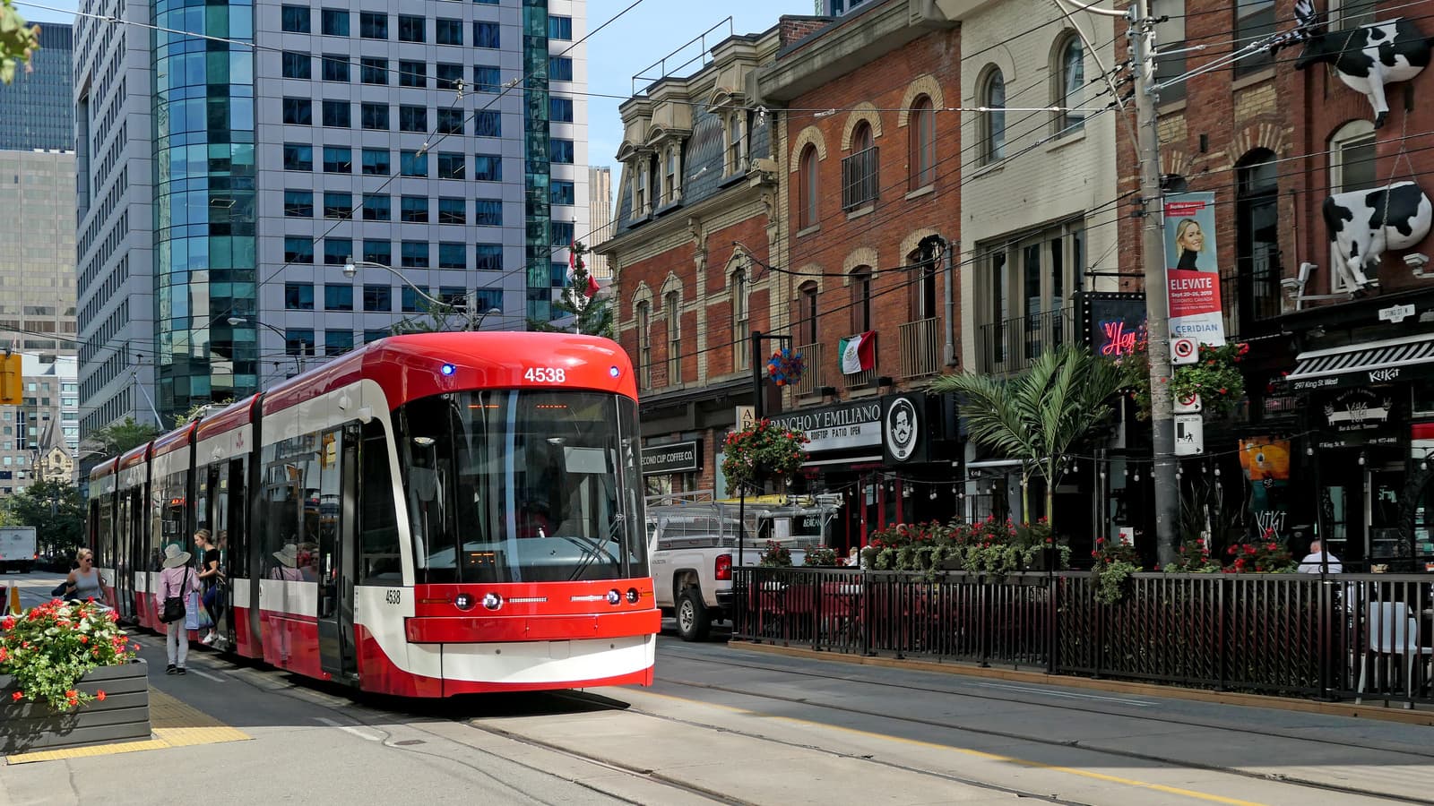 Modern red-and-white TTC streetcar travelling along a downtown Toronto street