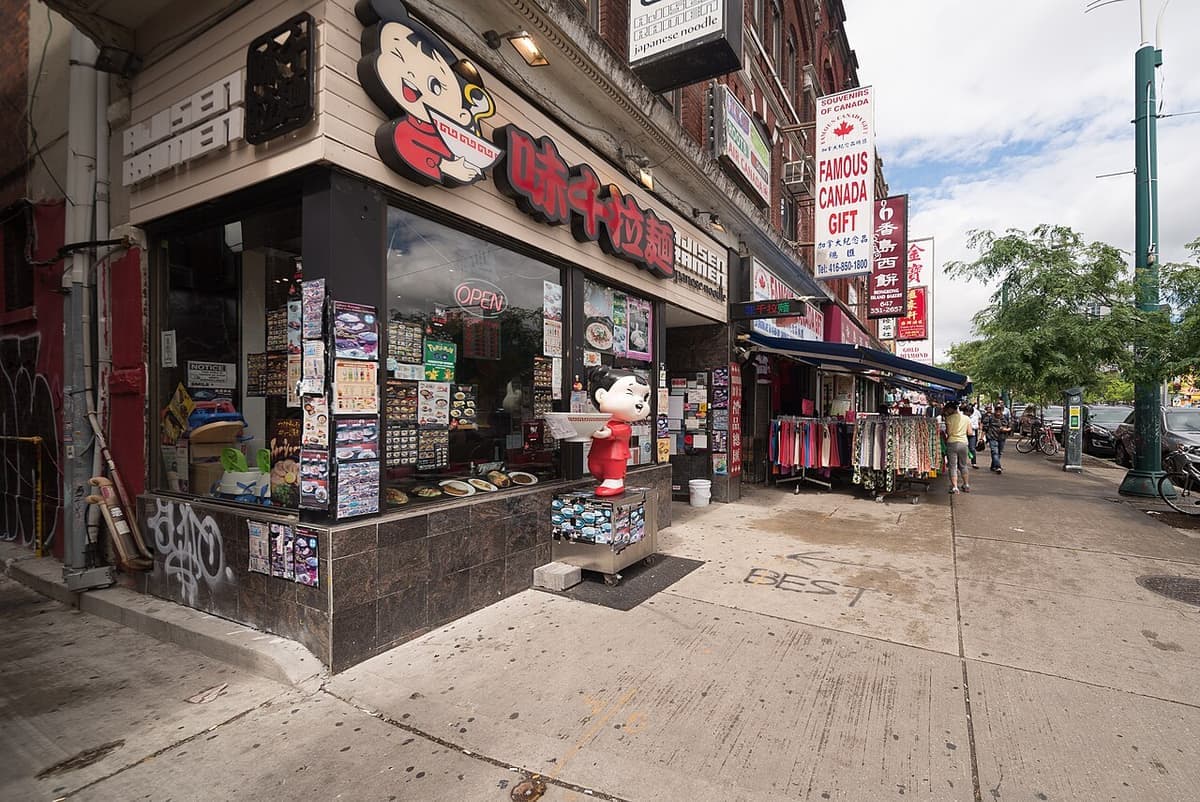 Shopfronts, signs and pedestrians on Spadina Avenue beside Kensington Market