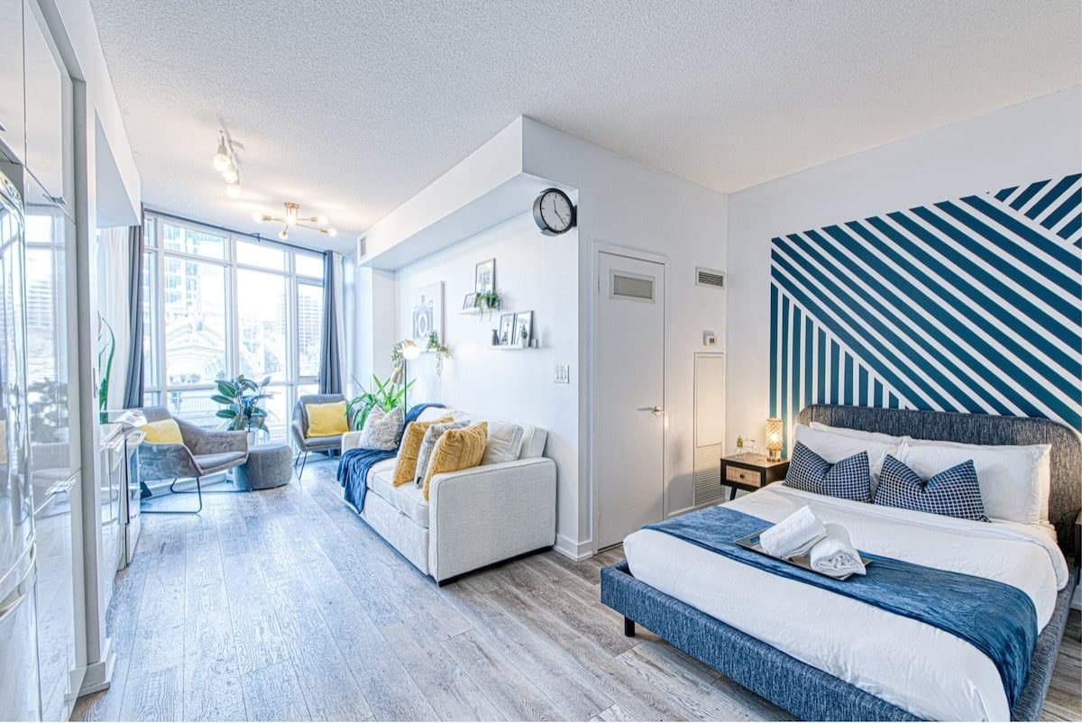 Bed and sofa sharing an open-plan Parade studio, with a blue geometric wall behind the bed