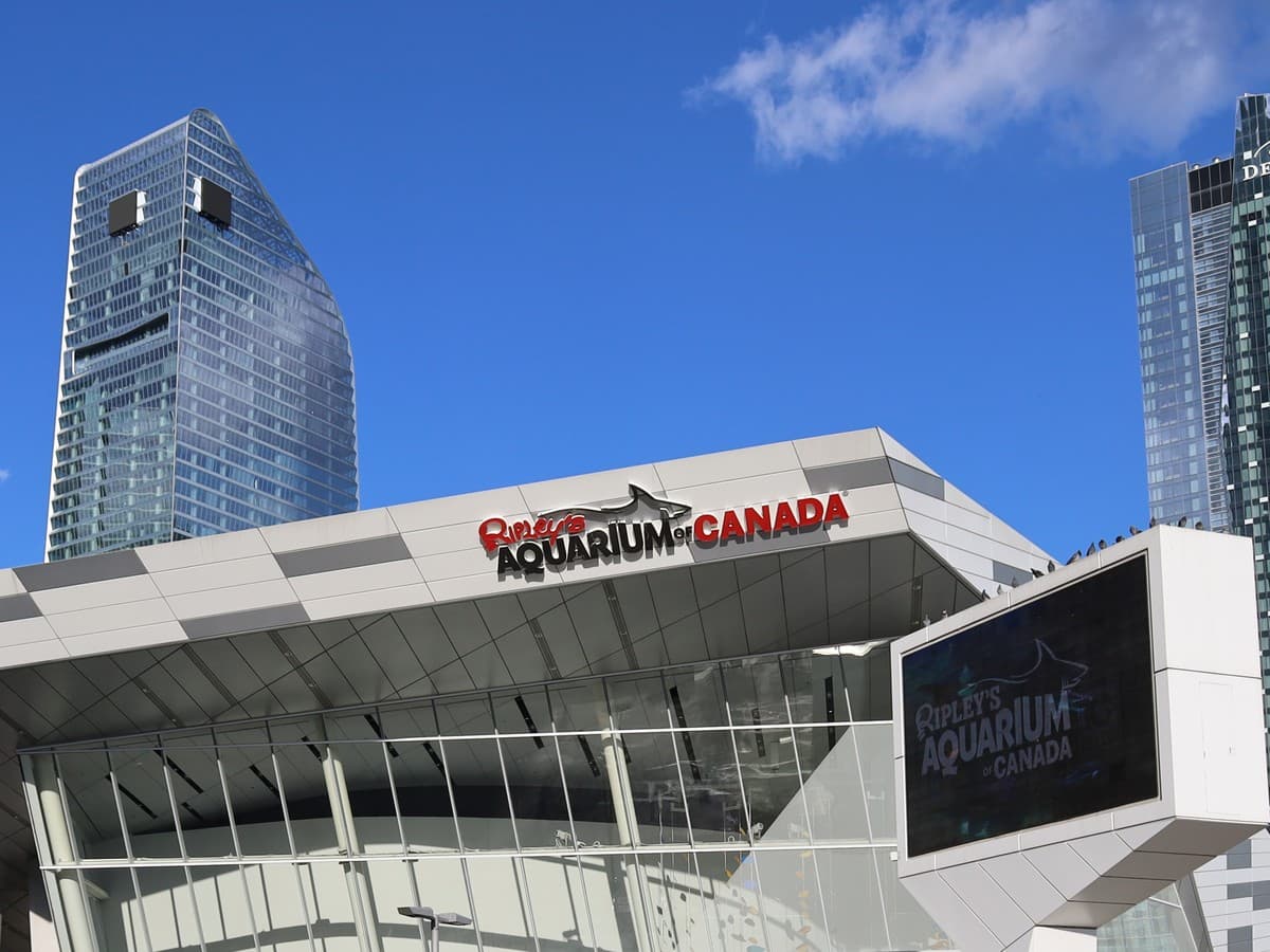 Ripley's Aquarium of Canada sign above the glass facade, with downtown towers and blue sky behind