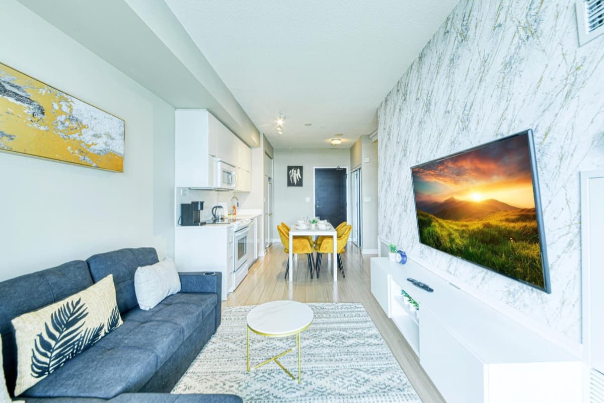 Living room, dining table and kitchen in a real Parade two-bedroom furnished suite in CityPlace, Toronto