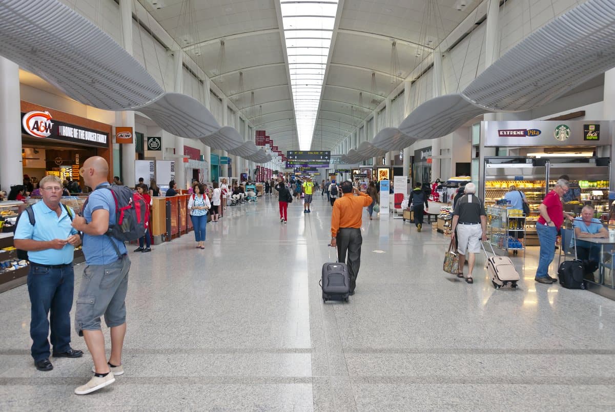 Travellers with luggage in the bright gate concourse of Toronto Pearson Terminal 1