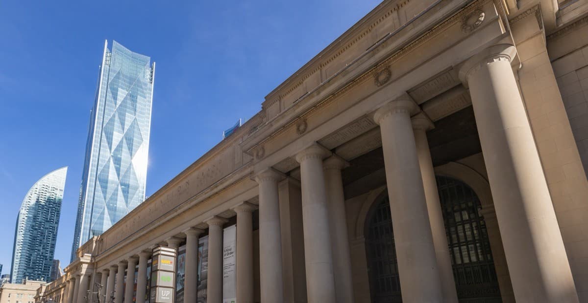 Stone columns and Front Street facade of Toronto Union Station beneath a blue sky